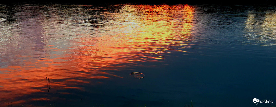 Napnyugta tükröződik Dunáról, S Ő oly távol!