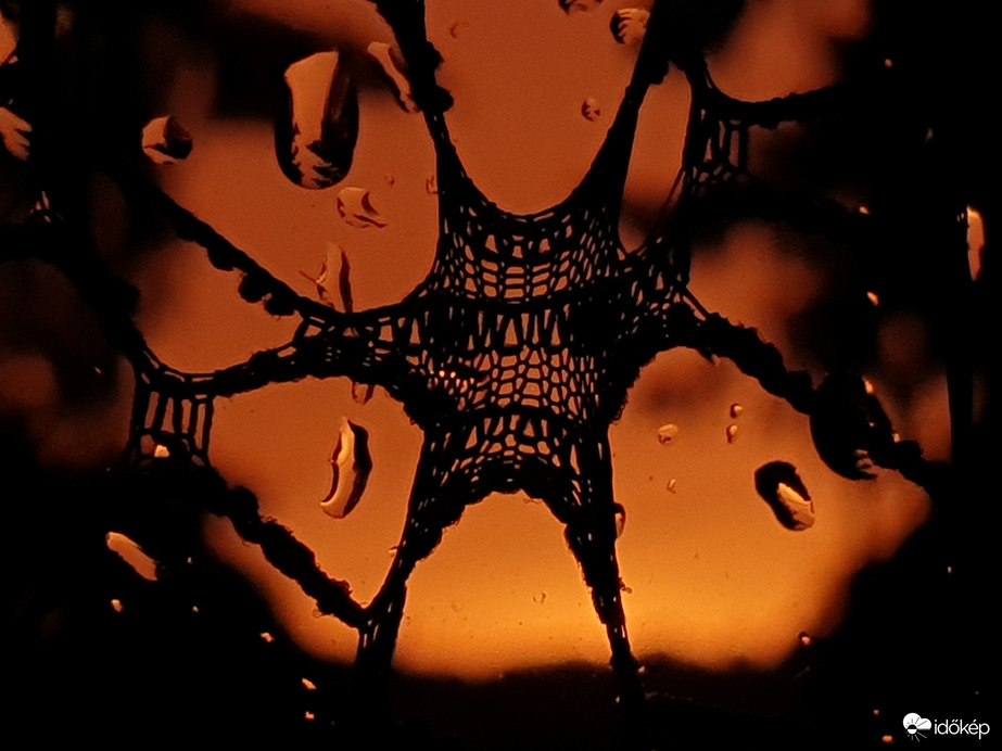 Esős, tüzes napnyugta a függönyön keresztül