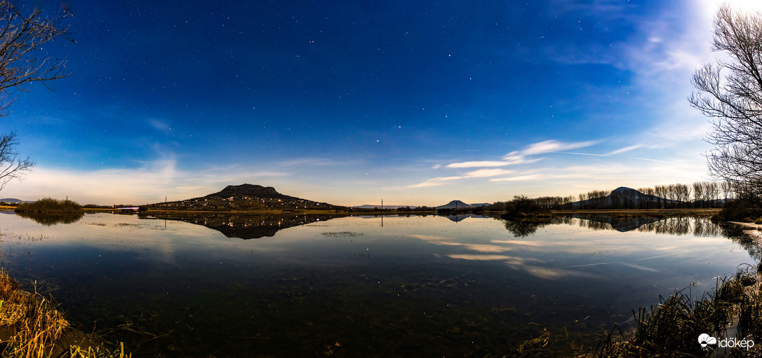 Holdfényes éjszakában a hegyek és a göncöl szekerének tükörképe a tóvá duzzadt belvízen. 