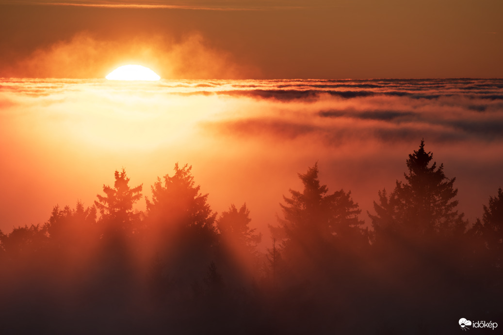 Színpompás, tüzes naplemente a ködtenger határán