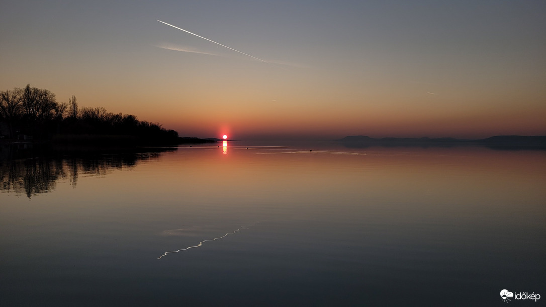 Kondenzcsík görbe estéje a víztükörben
